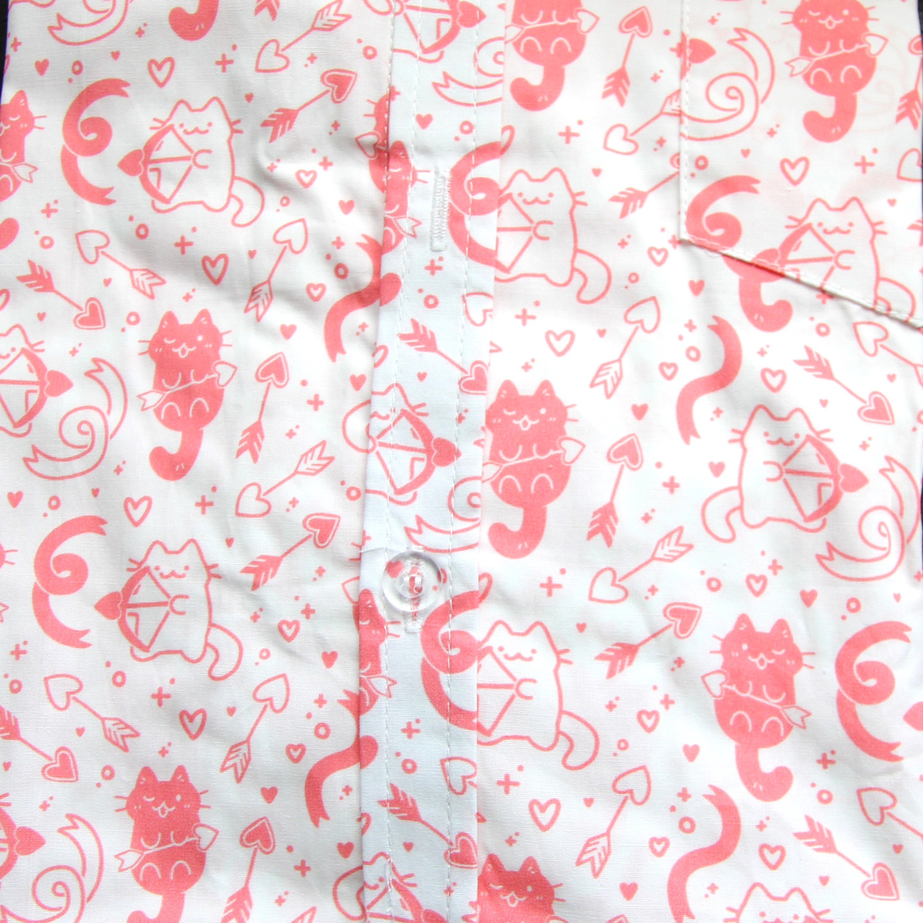 White button up shirt patterned with pink cats holding bows and arrows with heart-shaped arrowheads in a repeating pattern. The background features ribbons and hearts