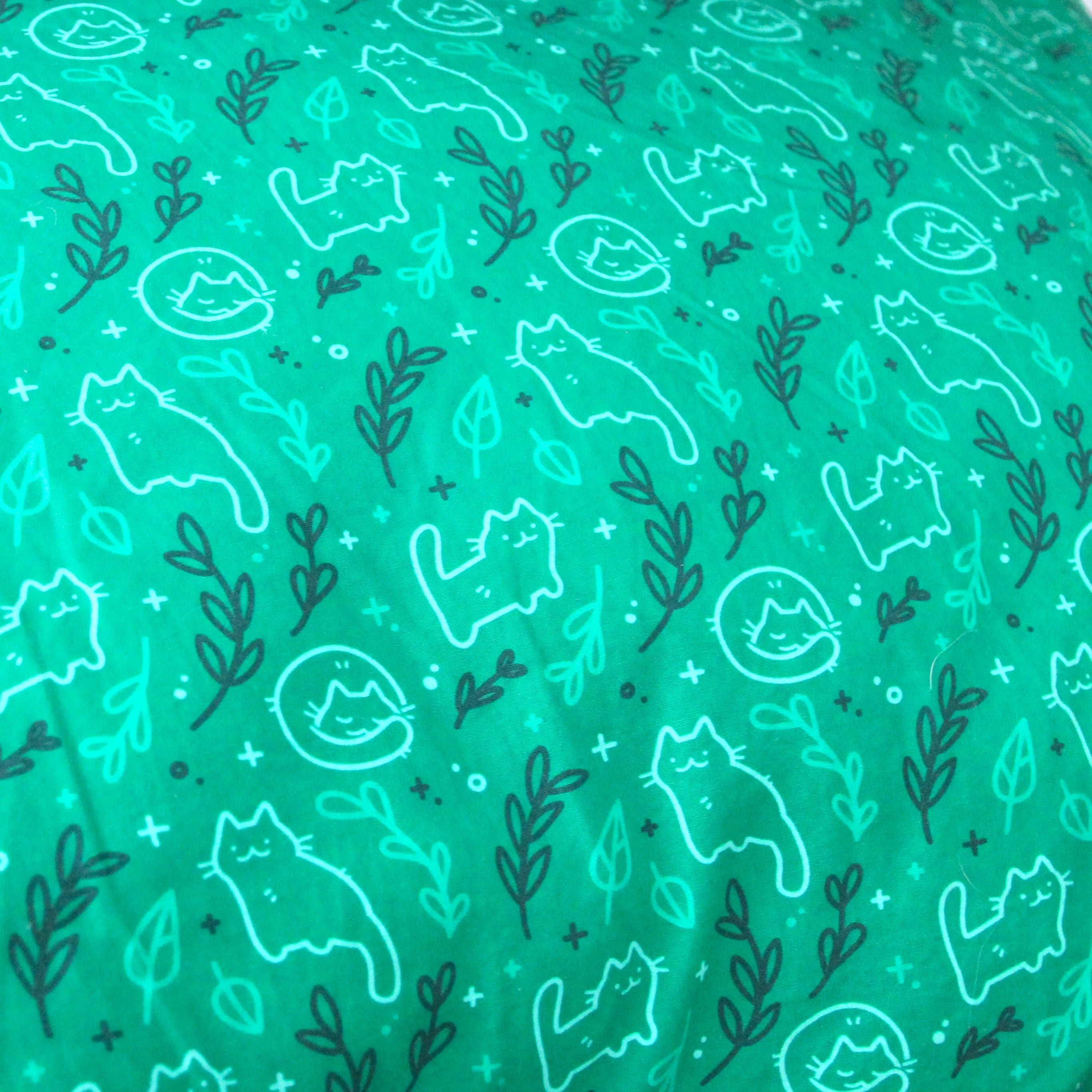 Green pillow case patterned with cats and leaves