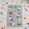 sticker sheet of cow cats wearing green ribbons, drawn in a cutesy style