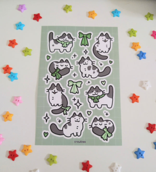 sticker sheet of cow cats wearing green ribbons, drawn in a cutesy style
