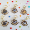 six different keychains featuring cats sitting in cardboard boxes