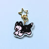 Clear acrylic charm. Black husky keychain with golden star shaped clasp on a light blue background