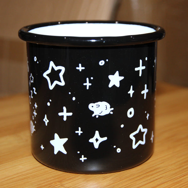 Black enamel mug with white interior. Design depicts a small running sheep surrounded by stars and sparkles