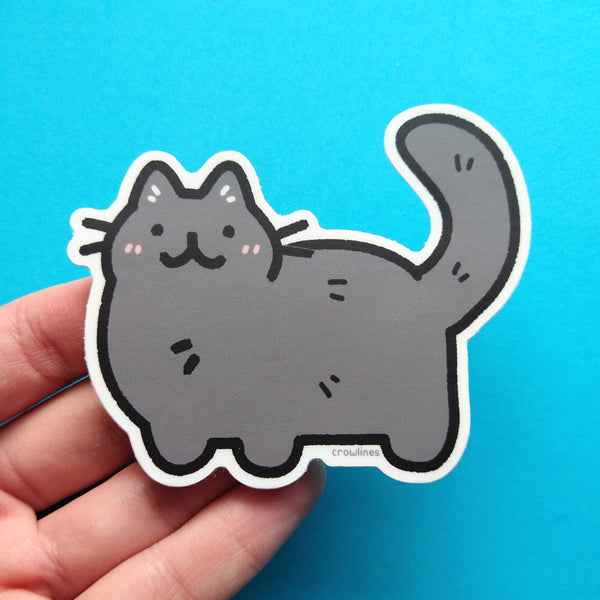 Sticker of a black cat. The cat is drawn in a cute style and has blush lines on its cheeks.