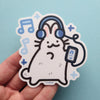 Sticker of a white rabbit listening to music on headphones surrounded by music notes