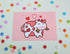 postcard mini print of a white and pink spotted cow drawn in a cute style on a pink background