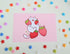 postcard mini print of a white cat holding strawberries with a pink background, drawn in a cute style