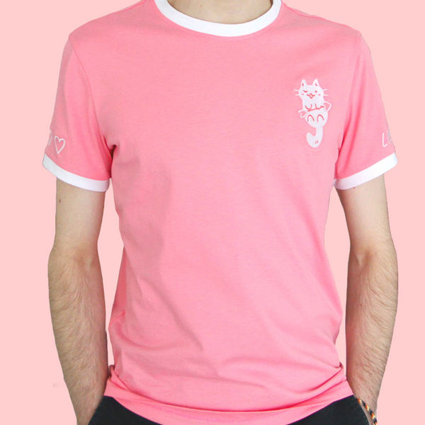Pink ringer tee with white neck and sleeve trim. The chest features an embroidered white cat holding a heart-shaped arrow. The right sleeve (left for viewer) is embroidered with three small white hearts. The left sleeve (right for viewer) is embroidered with the words "LOVE SHOT!" All of the embroidery is white.