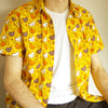 yellow button up shirt patterned with chickens and stars, worn unbuttoned over a plain white tee