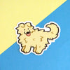 vinyl sticker of a fluffy yellow dog with folded ears, sticking its tongue out