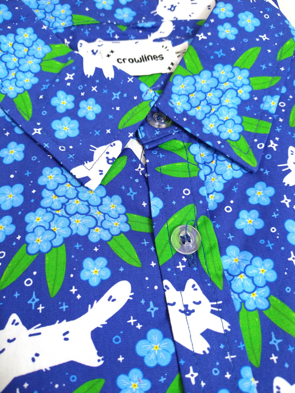 blue button up shirt patterned with white cats and forget me not flowers