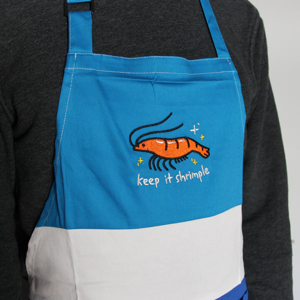 Color block apron with blue and white cotton. Embroidered with cute shrimp with text "keep it shrimple"