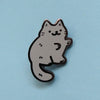 Hard enamel pin of a little gray cat drawn in a cute style