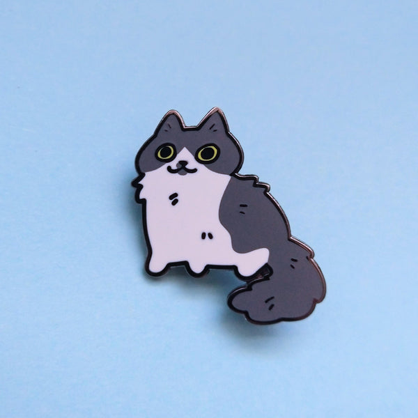 Hard enamel pin of a gray and white cat with big round yellow eyes