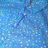 Blue button up shirt patterned with stars and sprinkles. The sprinkles are pink, yellow, white, and light blue. The shirt has pink star-shaped buttons.