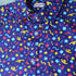 Dark blue button up shirt patterned with confetti. The color scheme is blue, red, and yellow.
