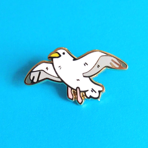 Gold plated hard enamel pin of a seagull in flight, wings outstretched