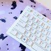 Light purple desk mat patterned with bats and cats, with white keyboard on top