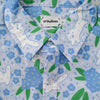 Light blue button up shirt patterned with cats and forget-me-not flowers. The color scheme is blue, white, and green.