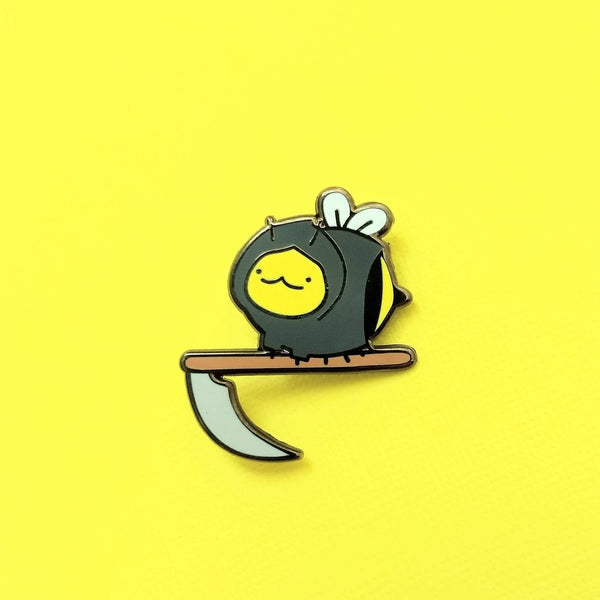 Hard enamel pin of a bee wearing grim reaper rope holding a scythe