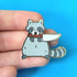 Gold plated hard enamel pin of a cute raccoon holding a kitchen knife